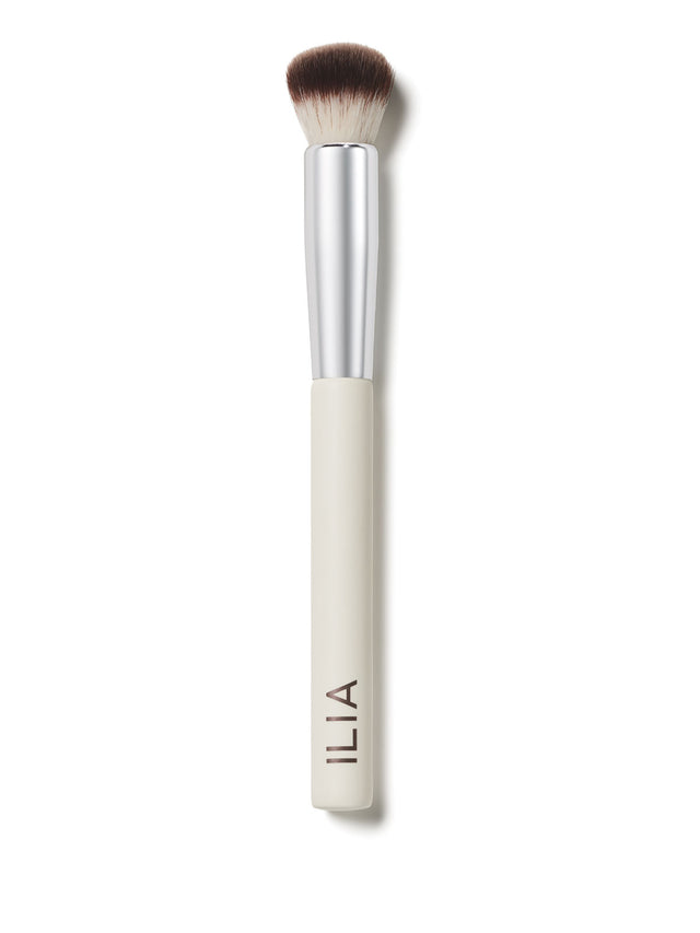A close-up of the Complexion brush with a white handle and soft, dual-toned bristles.
