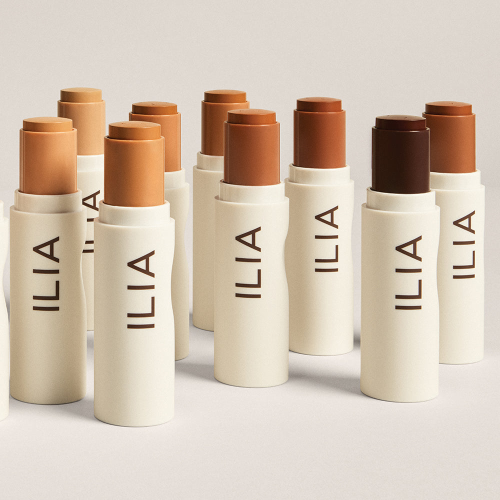 A range of shades in the ILIA Complexion Sticks standing upright on a grey background.