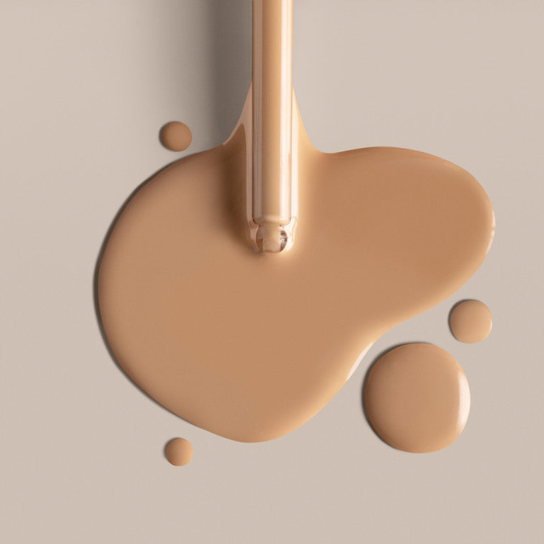 A close up of ILIA Super Serum Skin Tint dripping onto a smooth surface.