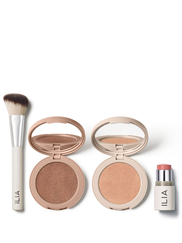 ILIA makeup essentials, featuring a sculpting brush, bronzer, highlighter, and blush stick, displayed on a white background.