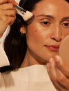 A person applies highlighting powder using the angled, Sculpting ILIA Brush.
