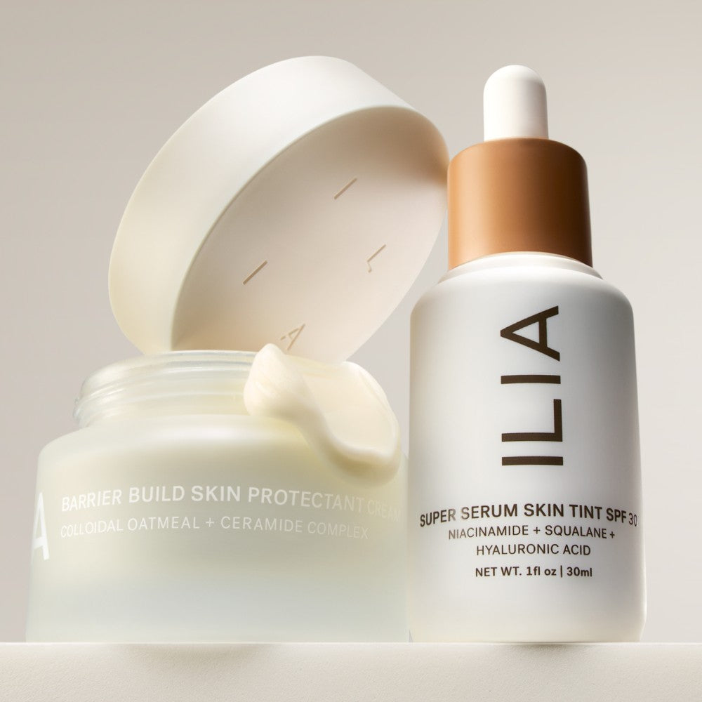ILIA Super Serum Skin Tint SPF 40 and Barrier Build arranged next to another on a shelf with a creamy swatch of Barrier Build.